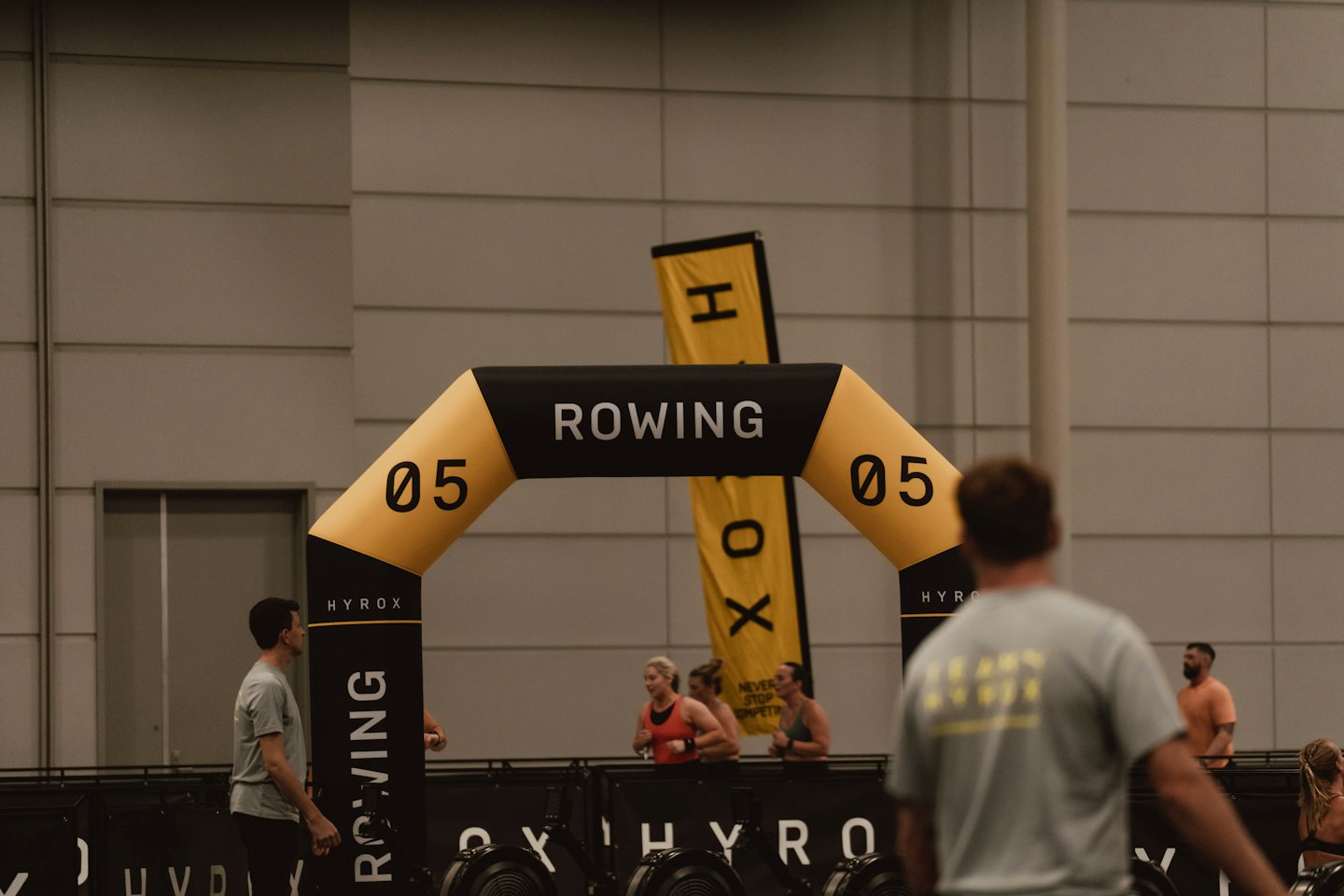 Athletes compete near a rowing station under an inflatable archway.